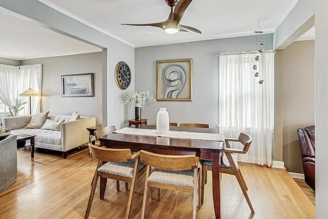 dining area featuring ceiling fan, ornamental molding, baseboards, and light wood-style floors