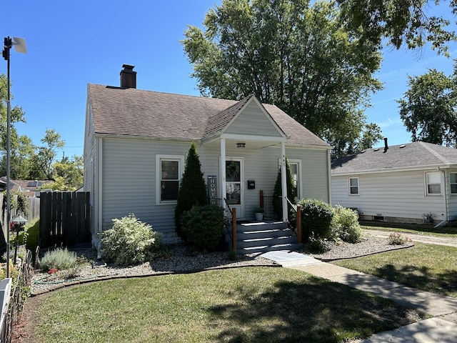 bungalow-style home featuring a front yard, covered porch, roof with shingles, and fence