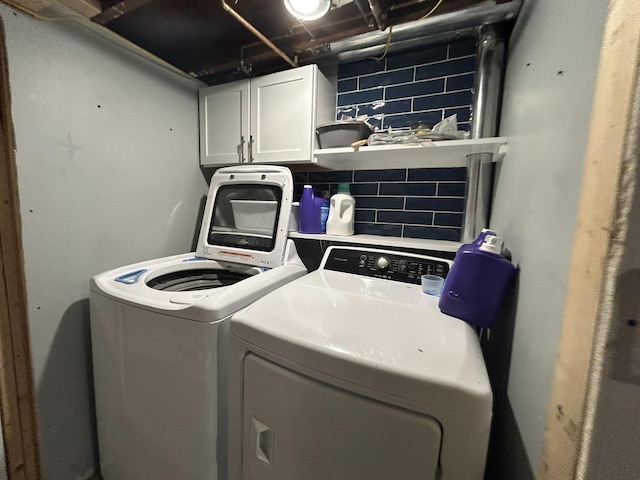 clothes washing area with washer and dryer and cabinet space