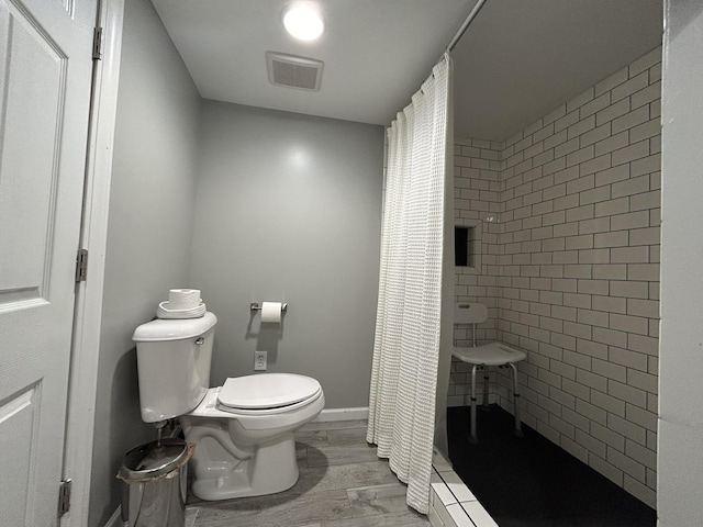 bathroom with visible vents, a shower stall, toilet, and wood finished floors