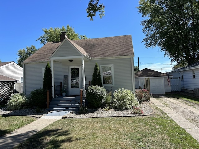 view of front facade with a shingled roof, a chimney, a detached garage, an outbuilding, and central AC