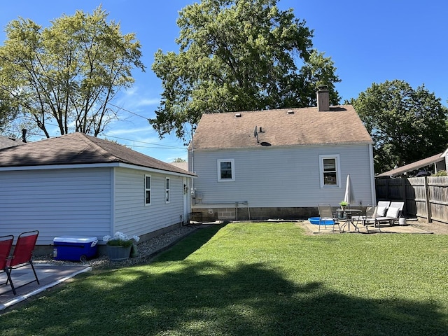 rear view of house featuring a patio, a yard, a chimney, and fence