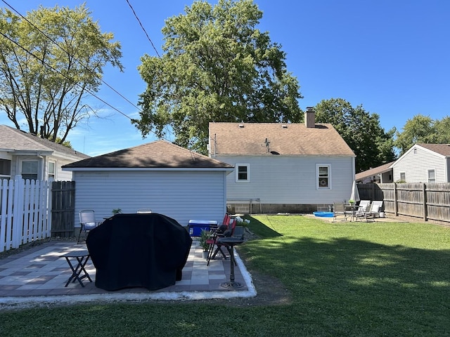 back of property featuring a yard, a chimney, a patio area, and a fenced backyard