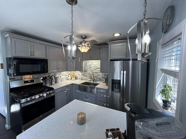 kitchen with decorative backsplash, hanging light fixtures, gray cabinets, stainless steel appliances, and a sink