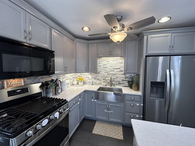 kitchen with appliances with stainless steel finishes, gray cabinets, light countertops, and a sink