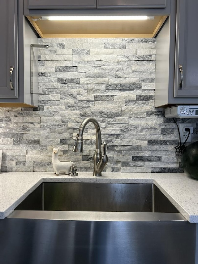 details featuring light countertops, tasteful backsplash, gray cabinets, and a sink