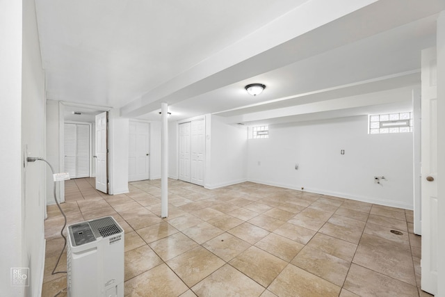 basement featuring light tile patterned floors and baseboards