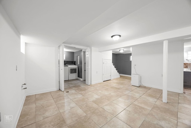 finished basement with light tile patterned floors, stairway, washer and clothes dryer, and baseboards