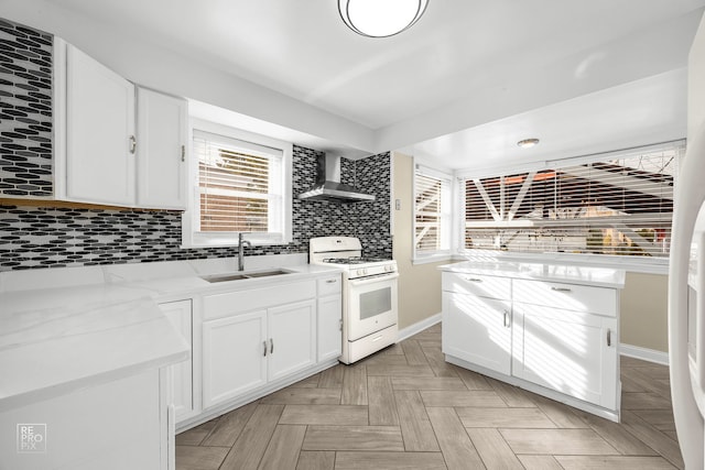 kitchen with a sink, white cabinetry, decorative backsplash, wall chimney exhaust hood, and white gas range