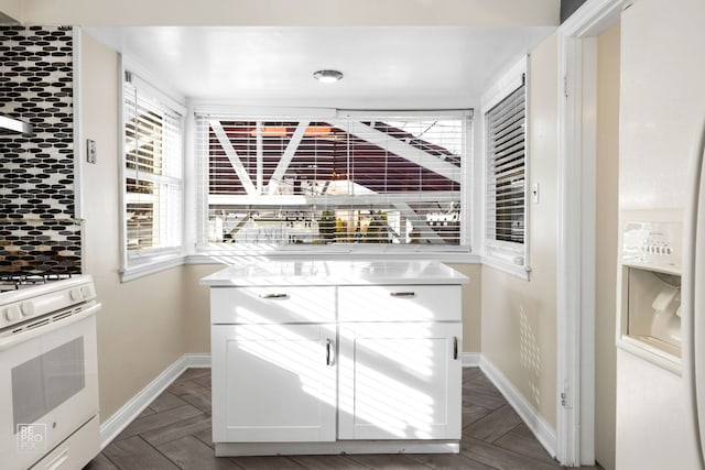 kitchen featuring white range with gas stovetop, baseboards, and light countertops