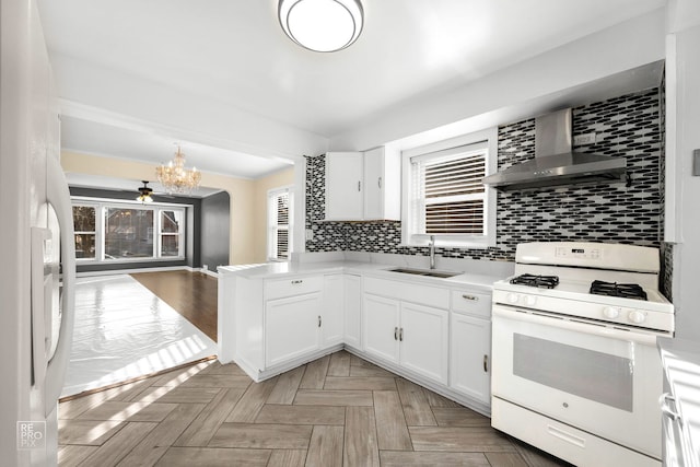 kitchen with white appliances, a sink, backsplash, and wall chimney exhaust hood