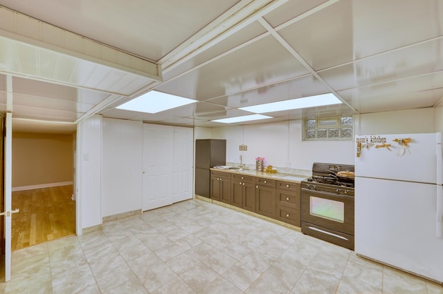 kitchen featuring light countertops, a drop ceiling, freestanding refrigerator, and black gas range oven