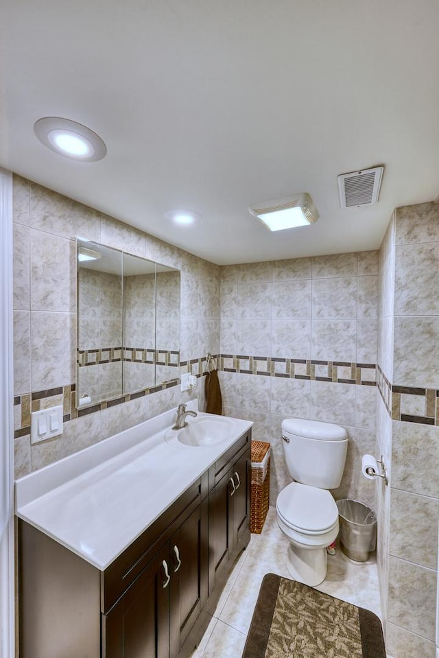 bathroom featuring tile patterned flooring, visible vents, tile walls, and toilet