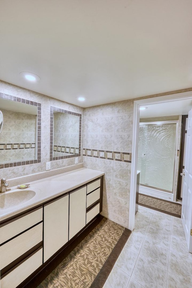 bathroom with a shower with door, tile patterned flooring, vanity, tile walls, and recessed lighting