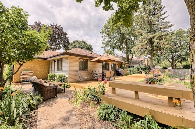 rear view of house featuring brick siding, outdoor lounge area, fence, and a wooden deck