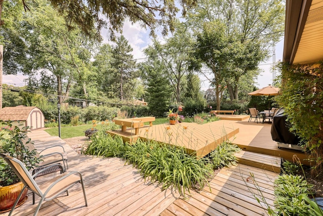 wooden terrace featuring a shed, outdoor dining area, and an outdoor structure