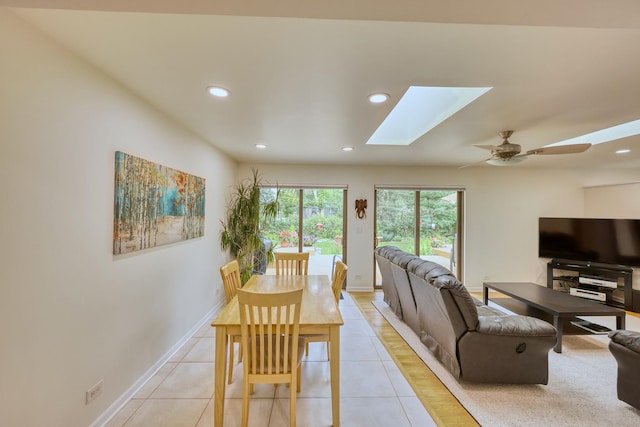 dining space featuring a skylight, light tile patterned floors, baseboards, a ceiling fan, and recessed lighting