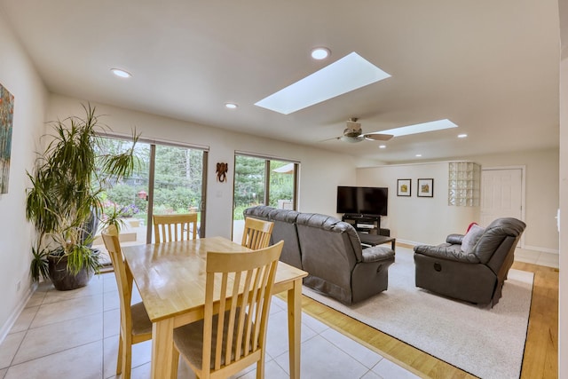 dining space featuring a skylight, light tile patterned floors, baseboards, and recessed lighting