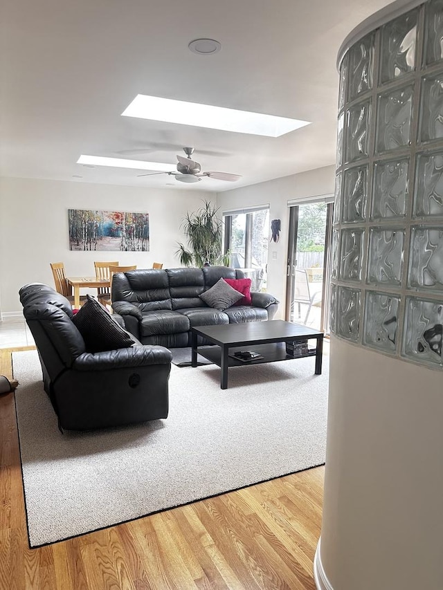 living room featuring a skylight, wood finished floors, and a ceiling fan