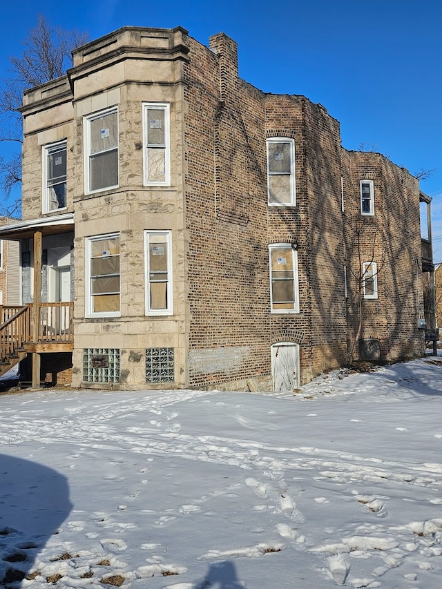 snow covered property featuring stone siding