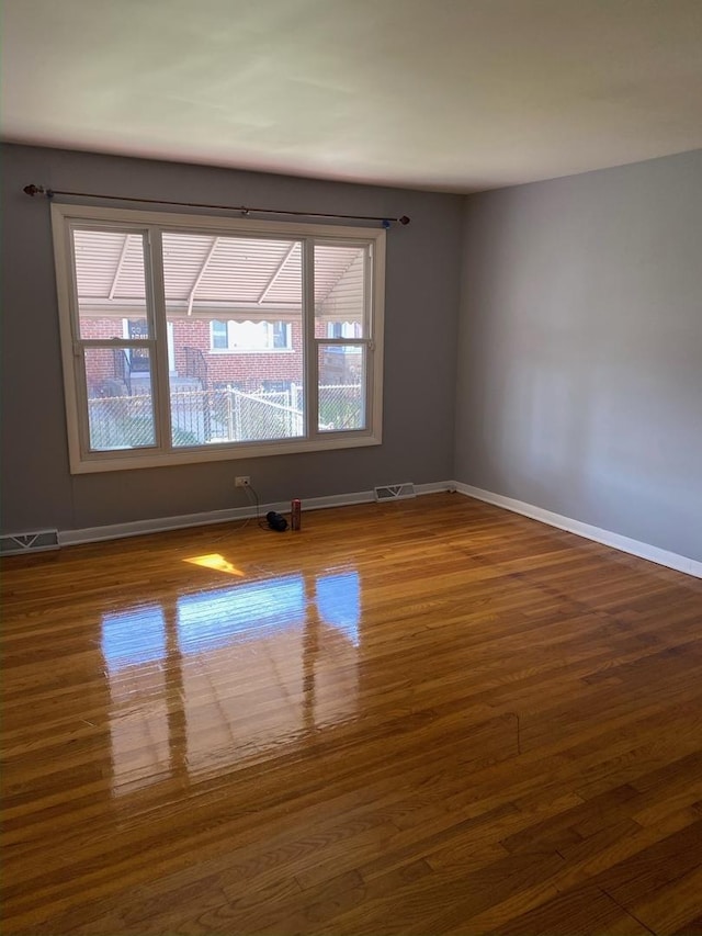 spare room with visible vents, baseboards, and wood finished floors