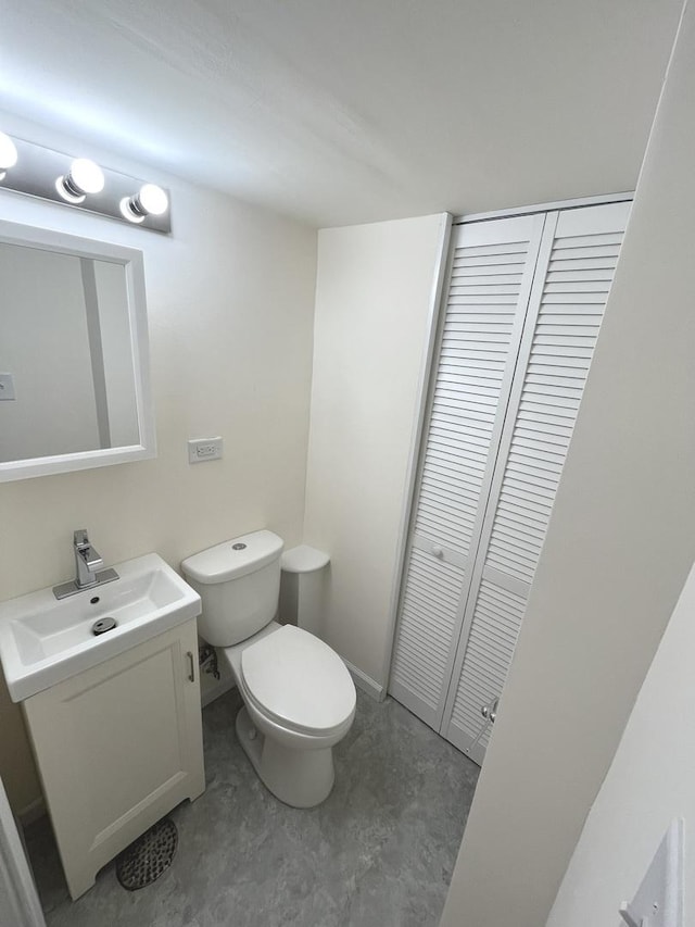 bathroom with concrete flooring, baseboards, vanity, and toilet