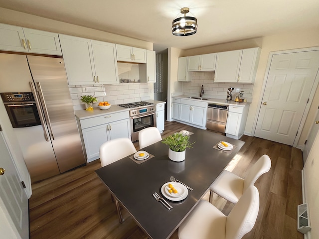 kitchen with appliances with stainless steel finishes, dark wood-style flooring, light countertops, white cabinetry, and a sink