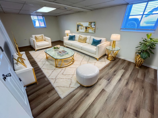 living room featuring wood finished floors, a paneled ceiling, and baseboards