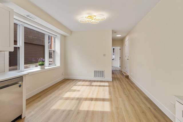 spare room with light wood finished floors, baseboards, and visible vents