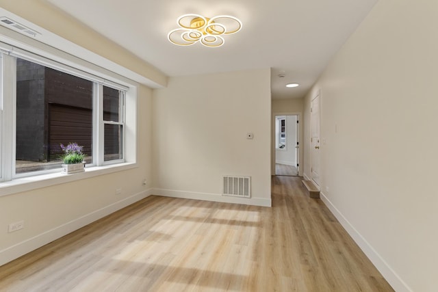 spare room featuring light wood-style floors, visible vents, and baseboards