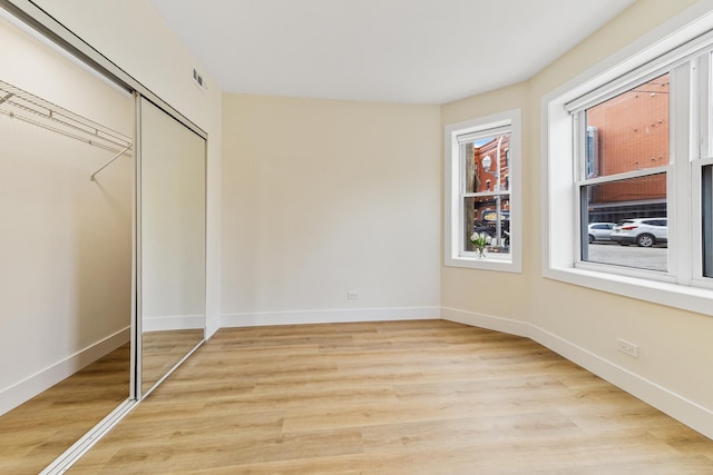 unfurnished bedroom with light wood-type flooring, a closet, visible vents, and baseboards