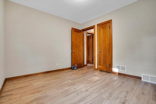 unfurnished bedroom with light wood finished floors, baseboards, and visible vents