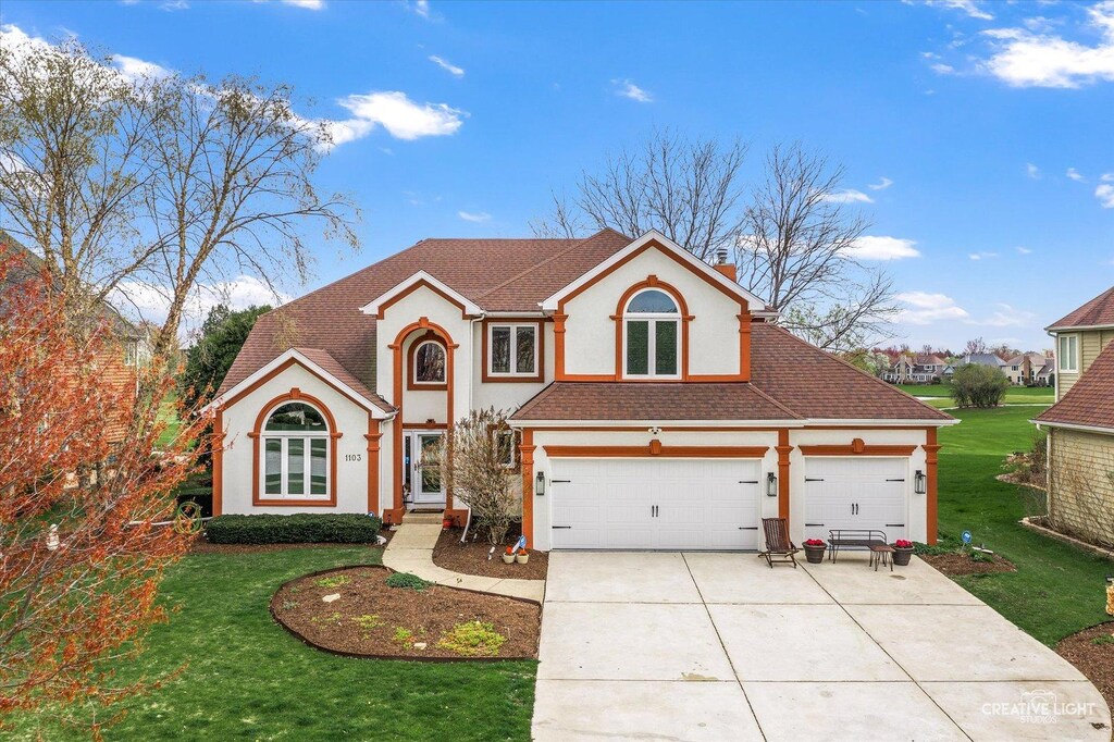 1103 Courtland Pl, Aurora, IL 60502 - traditional-style home with stucco siding, a shingled roof, a front lawn, and concrete driveway