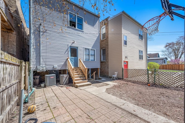 back of property with entry steps, fence, and central AC unit