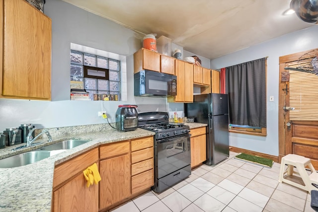 kitchen with black appliances, light tile patterned flooring, a sink, and light stone countertops