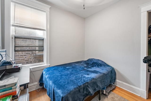 bedroom featuring multiple windows, baseboards, and wood finished floors