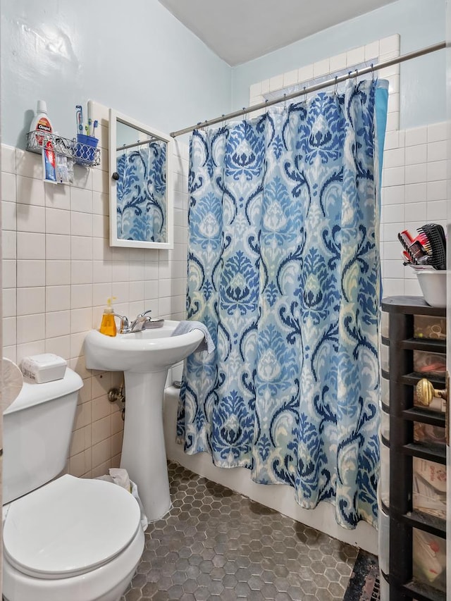 full bath featuring toilet, shower / bath combination with curtain, tile patterned flooring, and tile walls