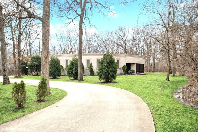 exterior space featuring curved driveway and a lawn