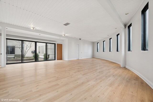 empty room with baseboards, a healthy amount of sunlight, and light wood-style flooring
