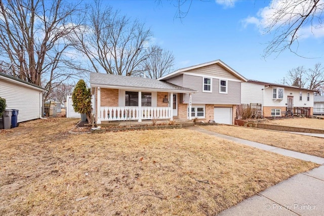 split level home featuring a garage, covered porch, roof with shingles, and brick siding