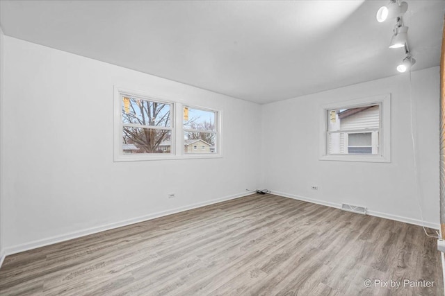 unfurnished room featuring baseboards, visible vents, and wood finished floors