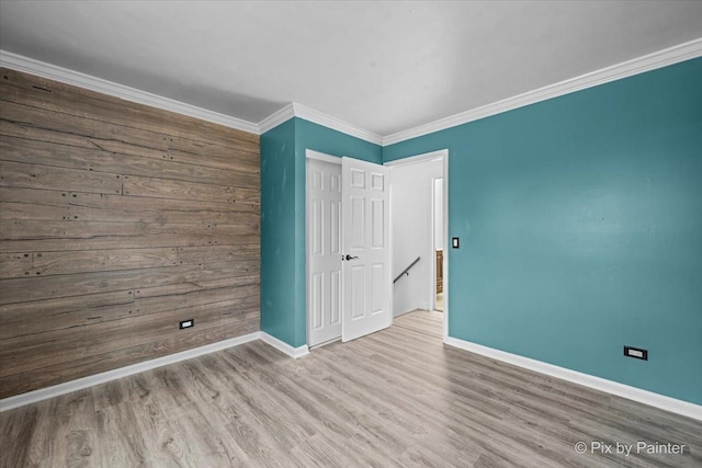 unfurnished bedroom featuring a closet, crown molding, baseboards, and wood finished floors