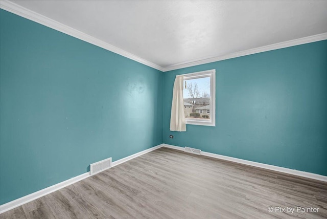 unfurnished room featuring baseboards, visible vents, wood finished floors, and ornamental molding