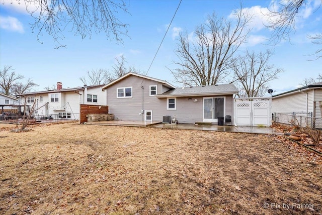 rear view of property featuring a gate, a patio area, fence, and a lawn