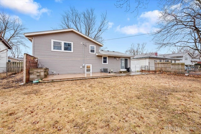 rear view of property featuring central AC, fence, a deck, and a lawn