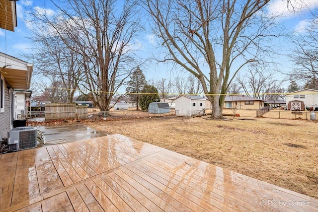 deck with an outbuilding, central AC, a fenced backyard, and a storage shed