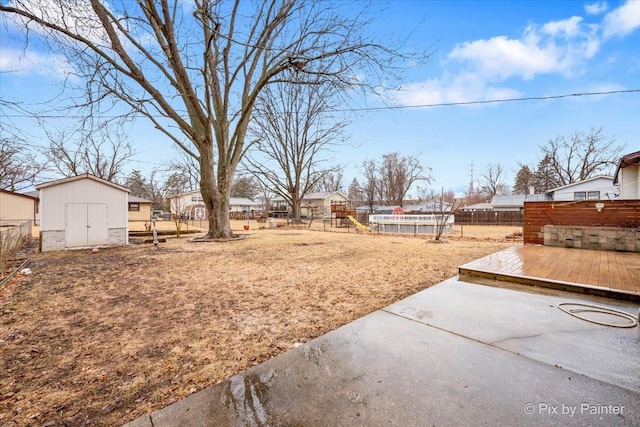 view of yard with an outbuilding, a patio, a playground, a fenced backyard, and a shed