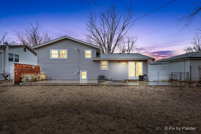 back of house at dusk featuring cooling unit, a patio area, and fence