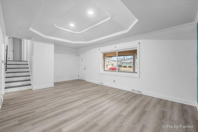 empty room with wood finished floors, visible vents, baseboards, stairs, and a tray ceiling