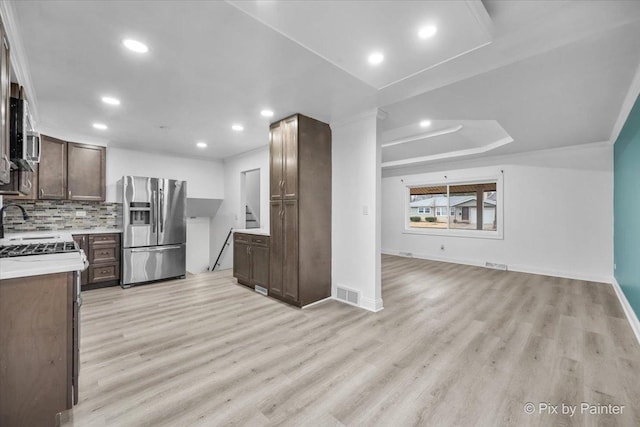 kitchen with stainless steel appliances, light countertops, open floor plan, and visible vents